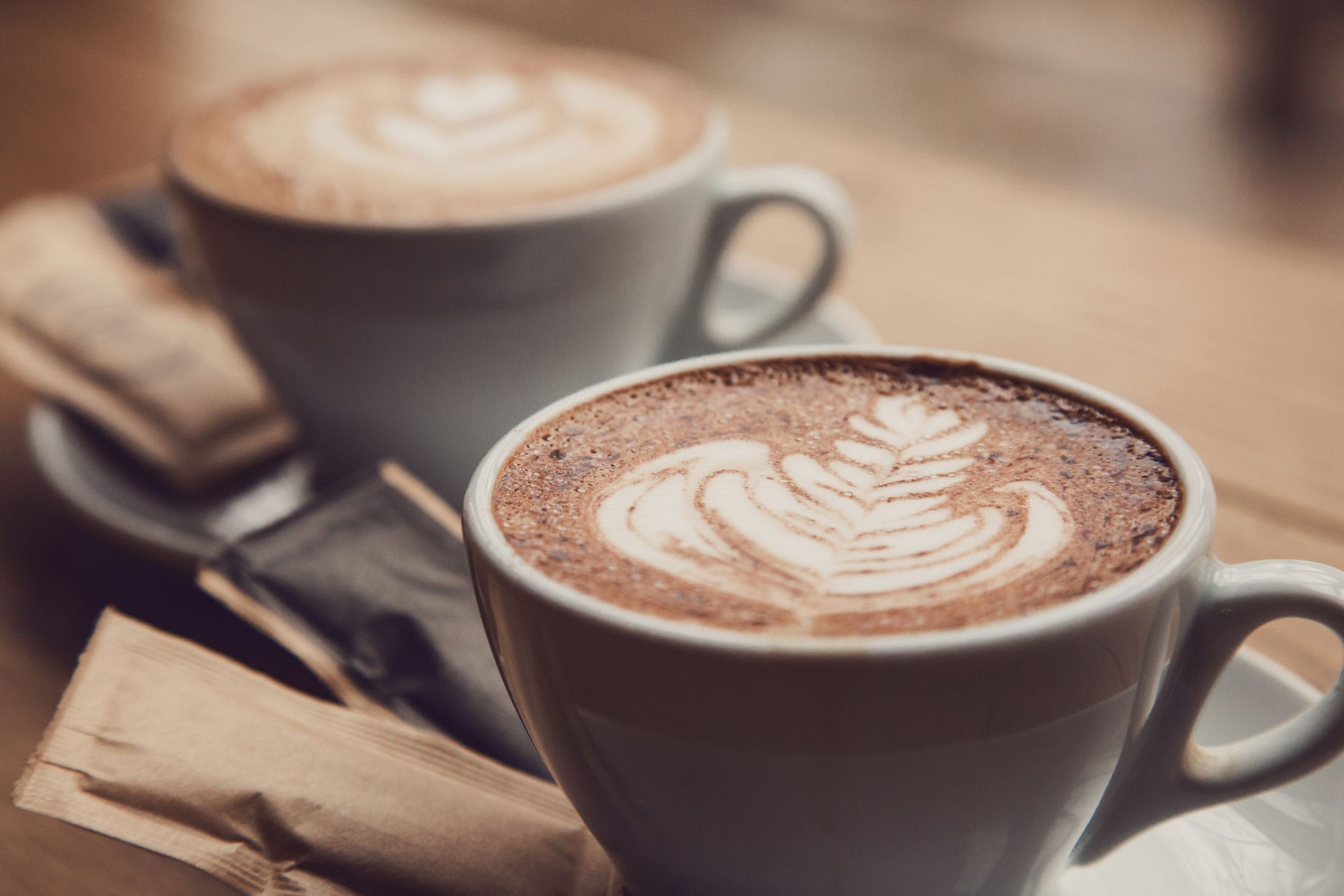 Two lattes sitting on a table
