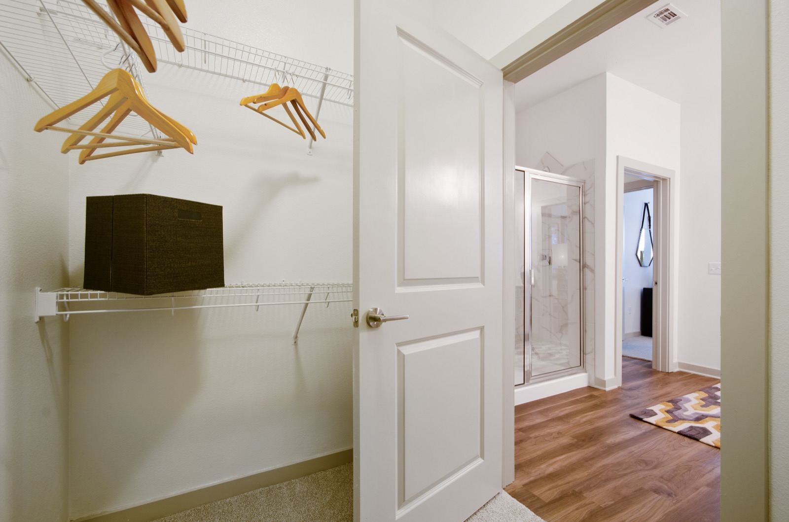 Garland Apartments- Spacious Walk-In Closet With White Shelving and Plush Carpet